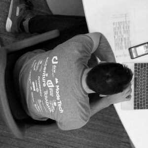 Attendee proudly wearing an event t-shirt with all the sponsor logo on the back while typing on a laptop