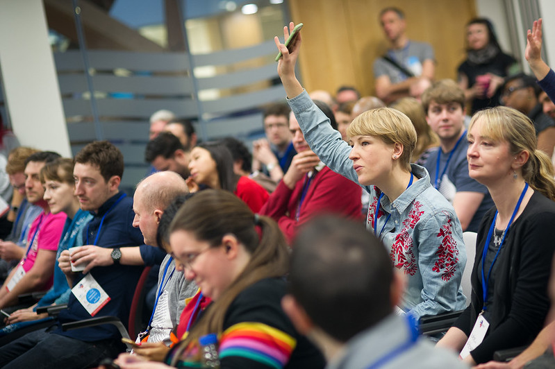 Excited gov camp attendee raising their hand to express interest in attending a session being pitched